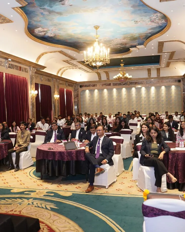 Business delegates seated at round tables in a chandeliered banquet hall