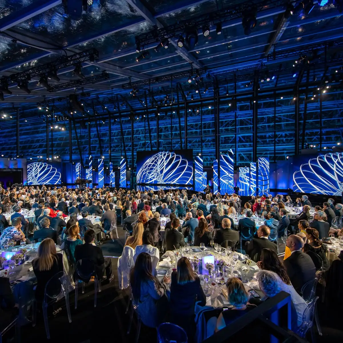 A packed hall facing a stage of LED screens at a launch evening